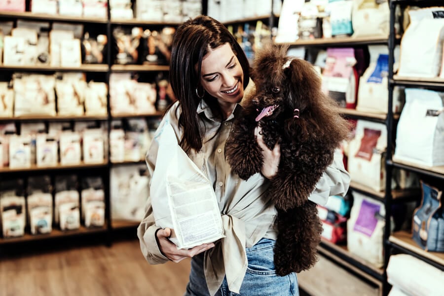 Una mujer comprando comida para perros con su perro