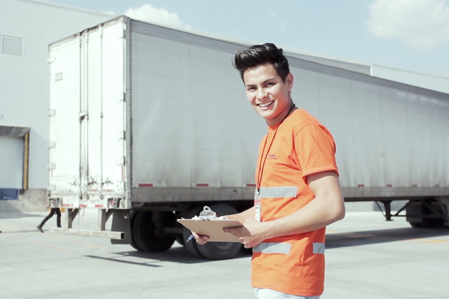 employee holding a writing board with a commercial trailer behind